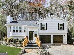 bi-level home featuring an attached garage, driveway, and a chimney