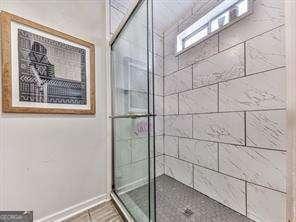 bathroom with tiled shower and baseboards