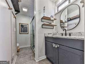 bathroom with baseboards, a stall shower, and vanity