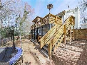 view of play area with a deck, a trampoline, fence, and stairs