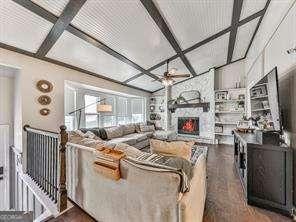 living room with ceiling fan, a large fireplace, coffered ceiling, and wood finished floors