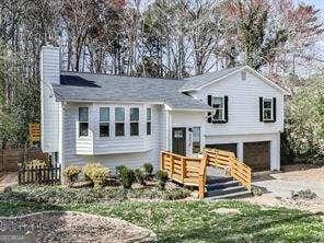 raised ranch featuring a garage, gravel driveway, and a chimney