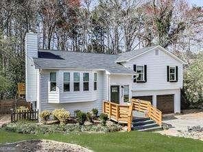 split foyer home featuring an attached garage, a chimney, gravel driveway, and a front yard