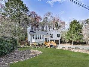 back of house featuring driveway, an attached garage, and a yard