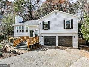 view of front of property with a chimney, driveway, and an attached garage