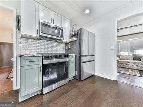 kitchen featuring backsplash, dark wood finished floors, appliances with stainless steel finishes, white cabinets, and a fireplace