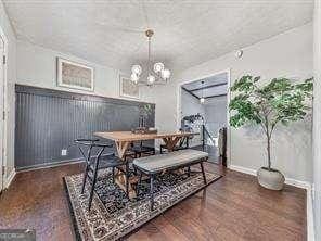 dining space with baseboards, an inviting chandelier, and wood finished floors