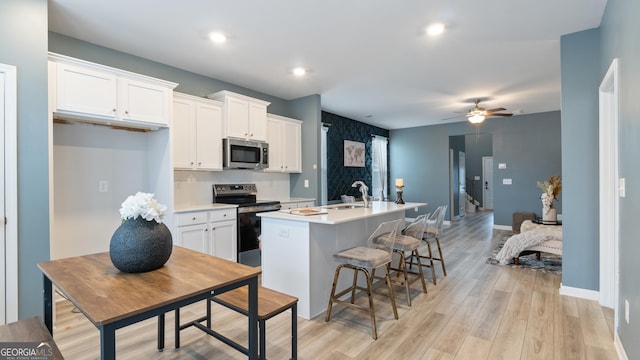 kitchen featuring a center island with sink, white cabinetry, stainless steel appliances, and a sink