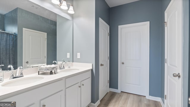 full bath with a sink, visible vents, wood finished floors, and double vanity