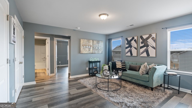 living area with plenty of natural light, visible vents, baseboards, and wood finished floors