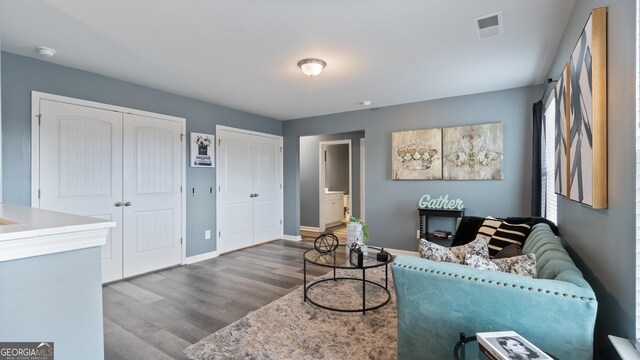 living room with visible vents, baseboards, and wood finished floors