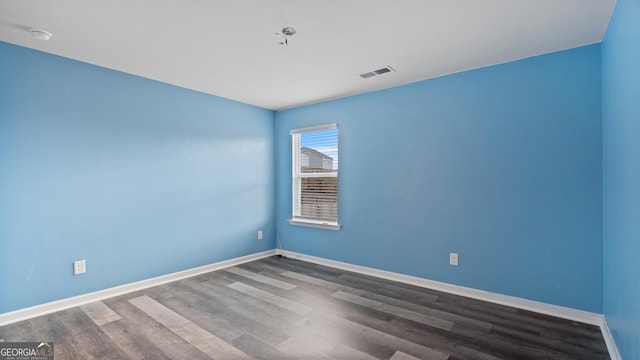 unfurnished room with visible vents, baseboards, and dark wood-type flooring