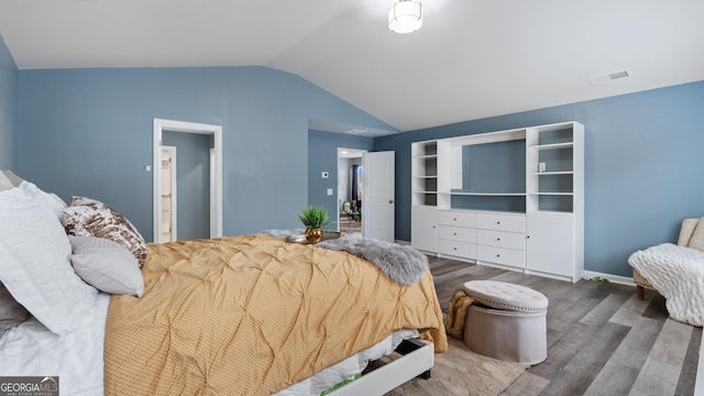 bedroom featuring visible vents, baseboards, lofted ceiling, and wood finished floors