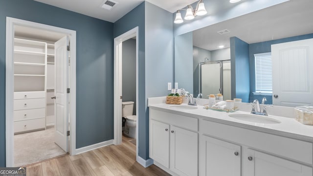 bathroom with visible vents, a shower stall, wood finished floors, and a sink