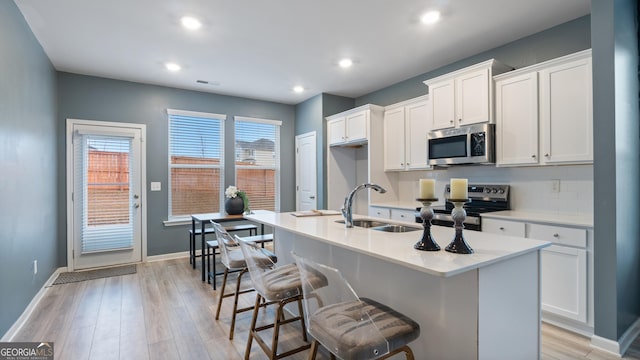 kitchen featuring light wood-type flooring, visible vents, a sink, backsplash, and stainless steel appliances