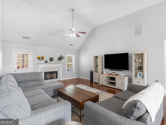 living area featuring a wealth of natural light, visible vents, a high end fireplace, and wood finished floors