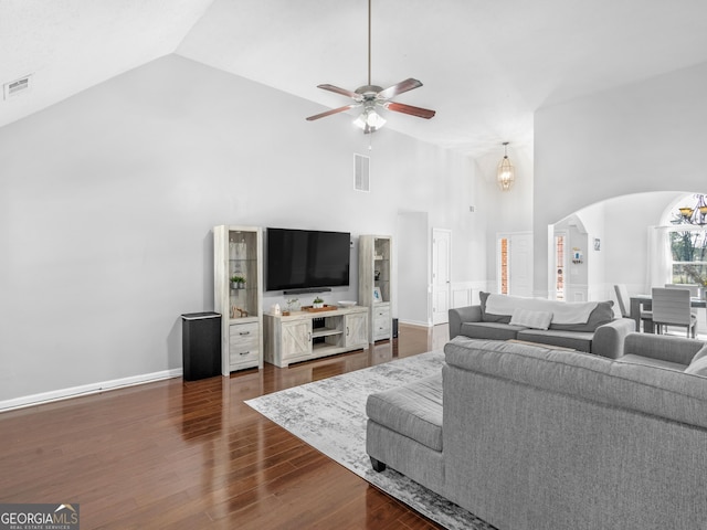 living area featuring arched walkways, visible vents, high vaulted ceiling, and dark wood-style flooring