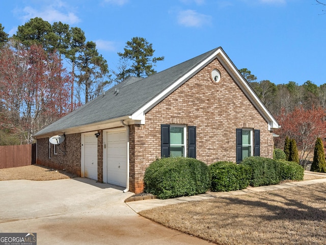 view of side of property featuring an attached garage, fence, brick siding, and driveway