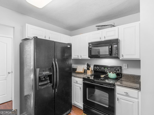 kitchen with wood finished floors, a textured ceiling, black appliances, and white cabinets