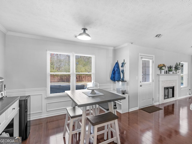 dining space featuring dark wood finished floors, a glass covered fireplace, visible vents, and a textured ceiling