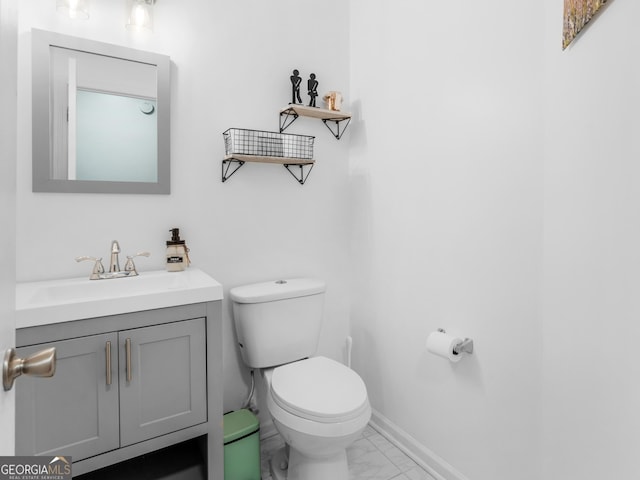 half bath featuring vanity, toilet, baseboards, and marble finish floor