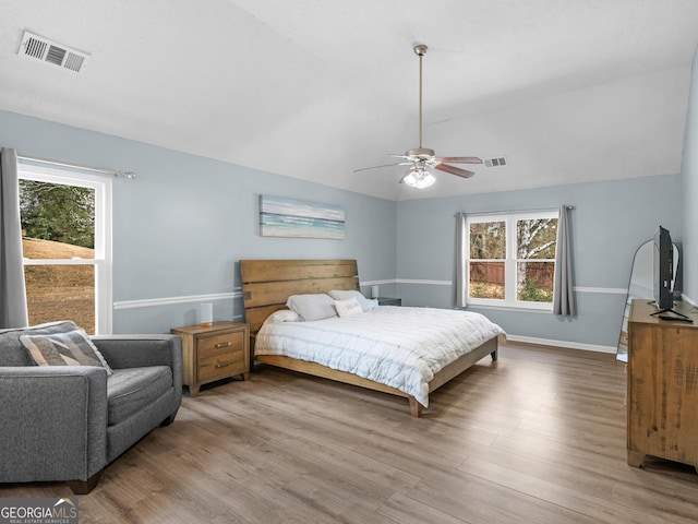 bedroom with visible vents, baseboards, lofted ceiling, and wood finished floors