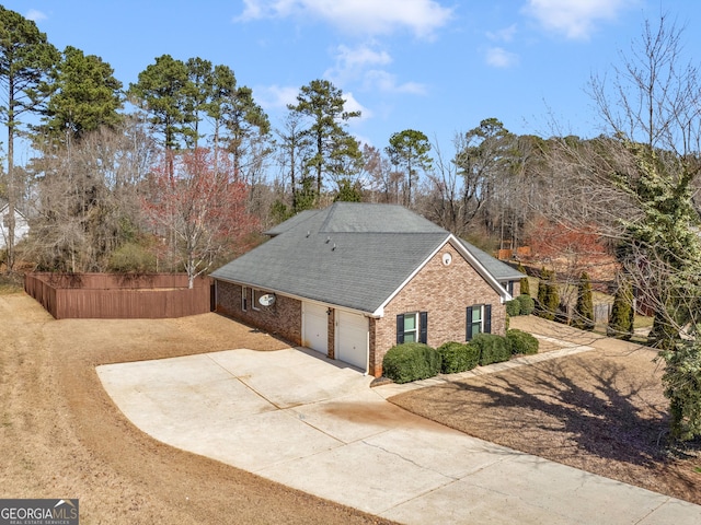 view of side of property featuring brick siding, driveway, a garage, and fence