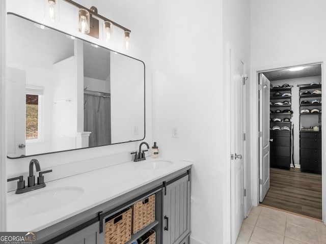 bathroom with double vanity, tile patterned floors, a spacious closet, and a sink