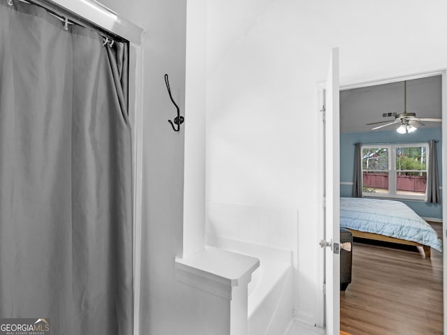 ensuite bathroom with a tub to relax in, ensuite bathroom, a ceiling fan, and wood finished floors