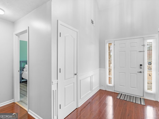 entryway featuring dark wood finished floors, a wainscoted wall, and visible vents