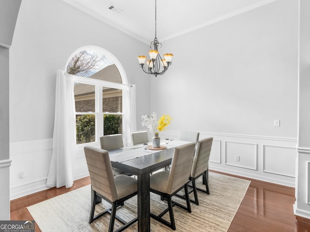 dining space with a notable chandelier, visible vents, ornamental molding, and hardwood / wood-style floors