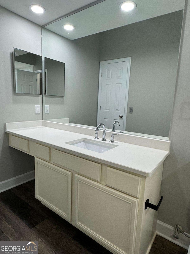 bathroom featuring vanity, recessed lighting, wood finished floors, and baseboards