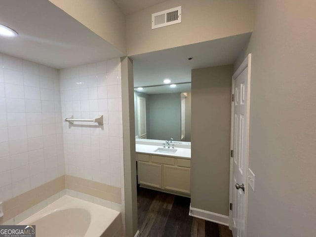 full bath with visible vents, a tub to relax in, wood finished floors, recessed lighting, and vanity