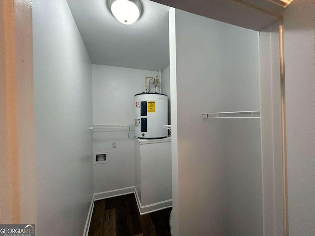 clothes washing area featuring washer hookup, water heater, laundry area, baseboards, and dark wood-style flooring