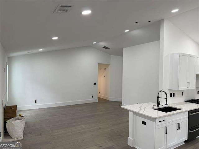 kitchen featuring lofted ceiling, white cabinets, visible vents, and a sink