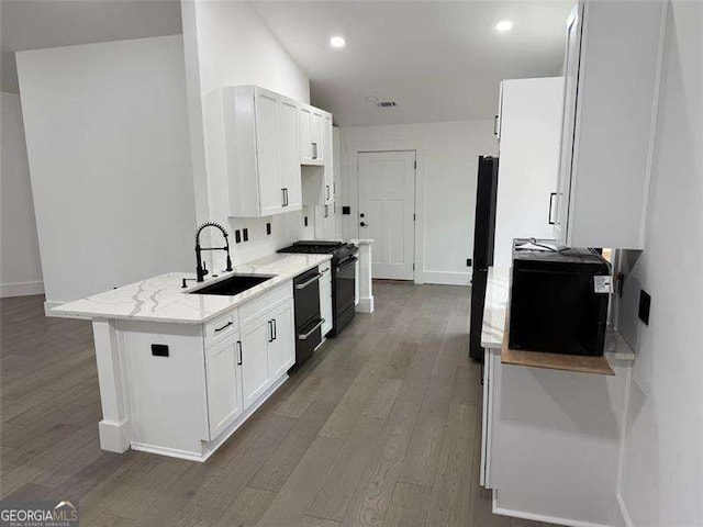 kitchen with light stone countertops, black gas stove, a sink, dark wood-type flooring, and white cabinets