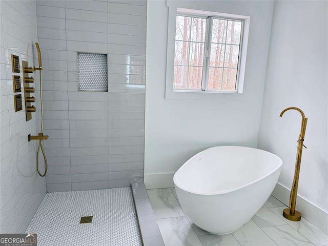 bathroom featuring baseboards, a soaking tub, marble finish floor, and a tile shower