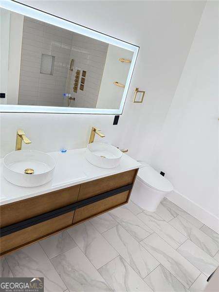 bathroom with double vanity, marble finish floor, toilet, and a sink