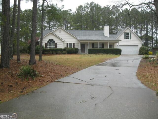 view of front facade with a front lawn, an attached garage, a chimney, and driveway