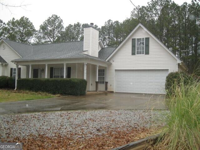 view of front of property featuring a chimney, an attached garage, and concrete driveway