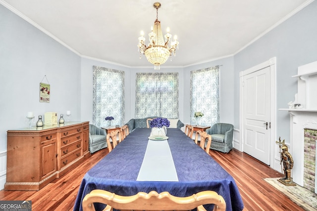 dining space with an inviting chandelier, wood finished floors, and ornamental molding