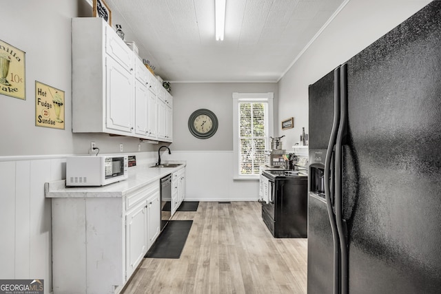 kitchen with a sink, light wood-style floors, black appliances, and white cabinets