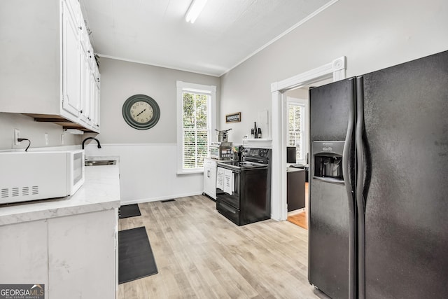 kitchen featuring black appliances, ornamental molding, light wood-style flooring, white cabinetry, and a sink