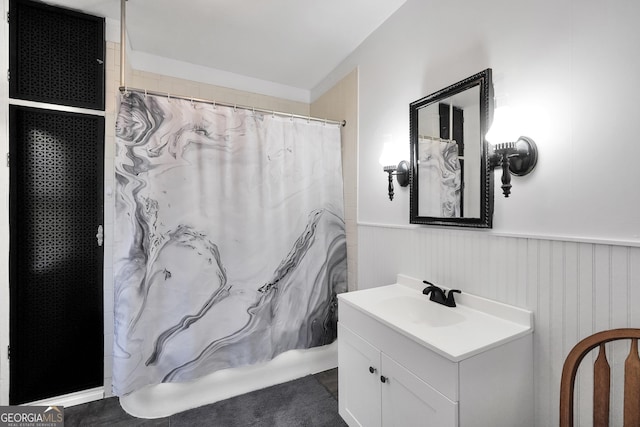 bathroom with curtained shower, vanity, and wainscoting