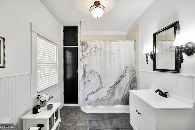 full bath featuring curtained shower, vanity, and wainscoting