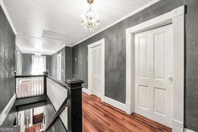 hall with crown molding, a notable chandelier, wood finished floors, and an upstairs landing