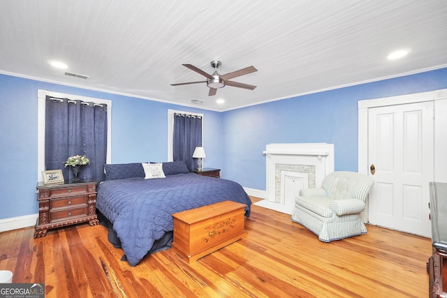 bedroom with crown molding, wood finished floors, visible vents, and baseboards