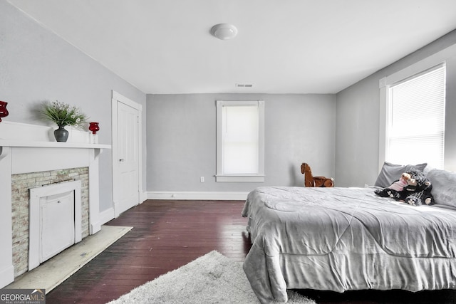 bedroom featuring visible vents, wood-type flooring, baseboards, and a fireplace