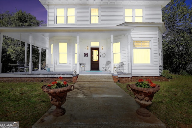 view of front of property with covered porch and a yard