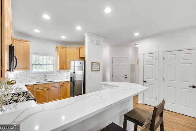 kitchen with light wood-type flooring, a sink, black microwave, stainless steel fridge with ice dispenser, and decorative backsplash